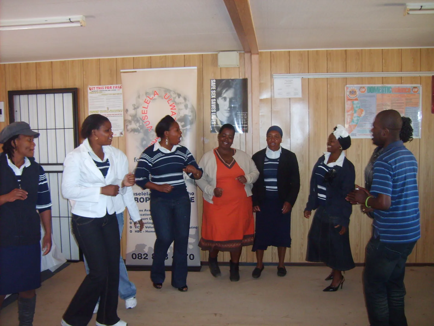 A group standing together indoors beside a Vuselela banner.